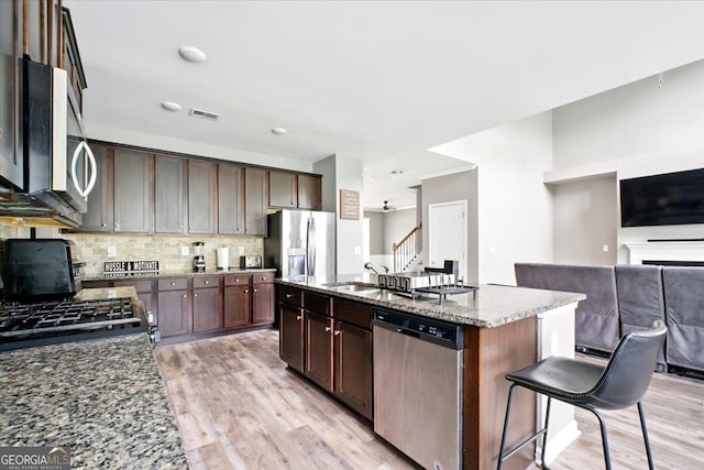 7698 Hansel Ln, Lithonia, GA 30058 - kitchen with stainless steel appliances, light wood-type flooring, a sink, and dark stone countertops