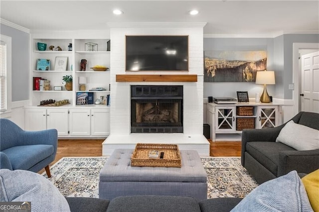living room with crown molding, recessed lighting, wood finished floors, and a fireplace