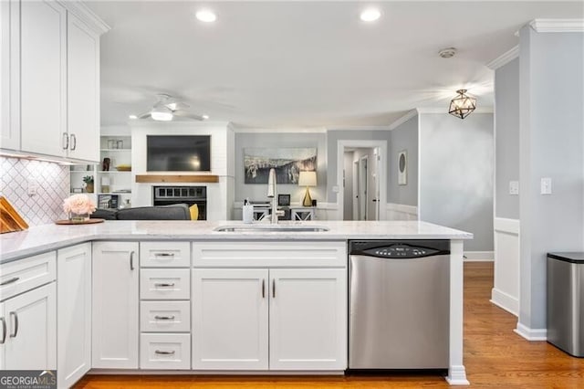 kitchen with white cabinets, a sink, a ceiling fan, open floor plan, and stainless steel dishwasher
