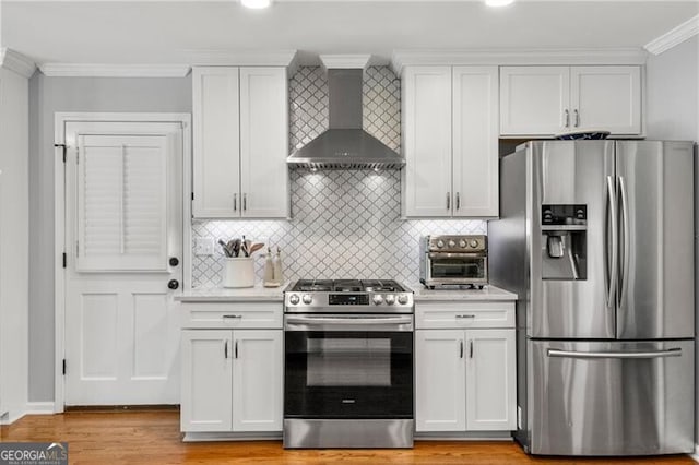 kitchen with a toaster, white cabinets, stainless steel appliances, and wall chimney exhaust hood