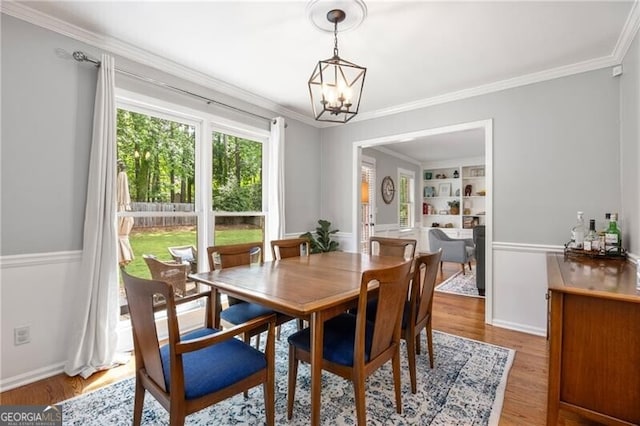 dining room featuring crown molding, light wood-style floors, and a notable chandelier