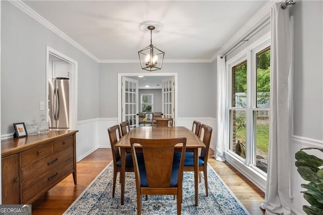 dining room featuring wainscoting, wood finished floors, and a notable chandelier