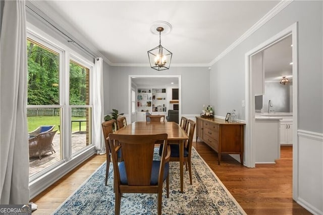 dining room with an inviting chandelier, ornamental molding, and light wood-type flooring