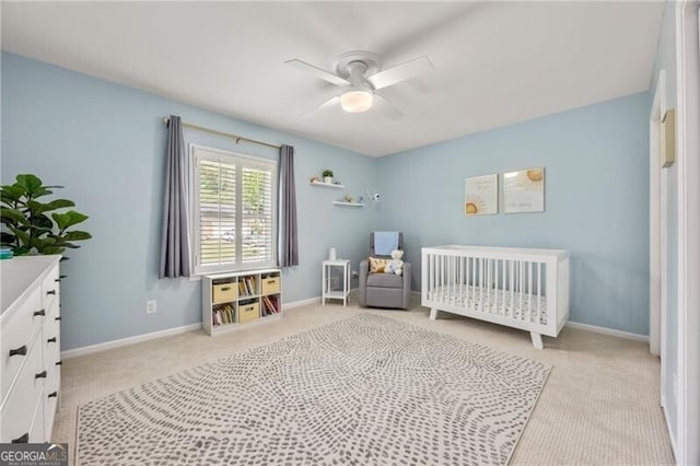 bedroom with a ceiling fan, baseboards, carpet, and a nursery area