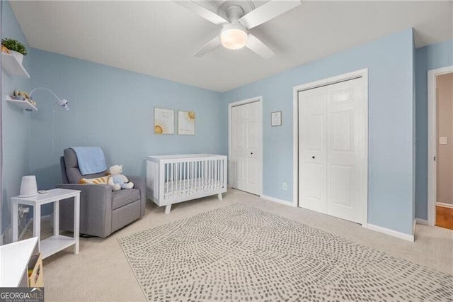 bedroom with baseboards, a ceiling fan, two closets, and light colored carpet