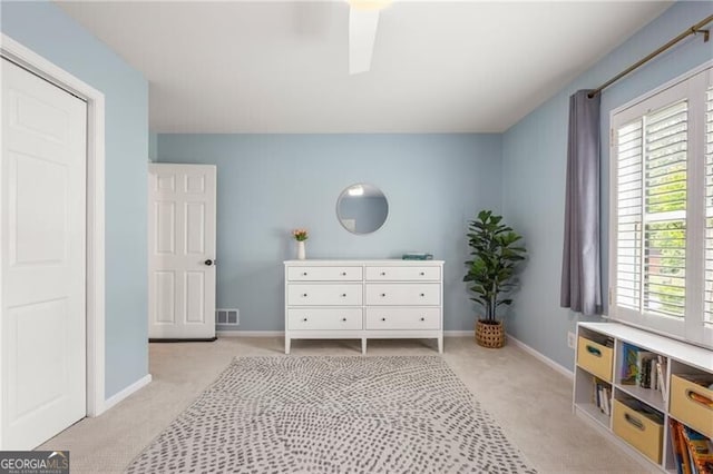 bedroom with baseboards, visible vents, light carpet, and ceiling fan