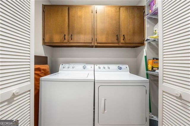 clothes washing area with washer and clothes dryer and cabinet space