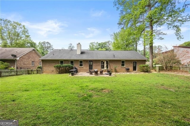 rear view of property with a lawn, a fenced backyard, a patio area, and a chimney
