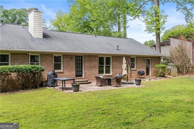 back of house with a lawn, a patio, a chimney, and brick siding