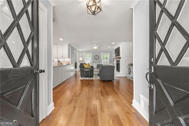 foyer with baseboards, ornamental molding, and light wood-style floors