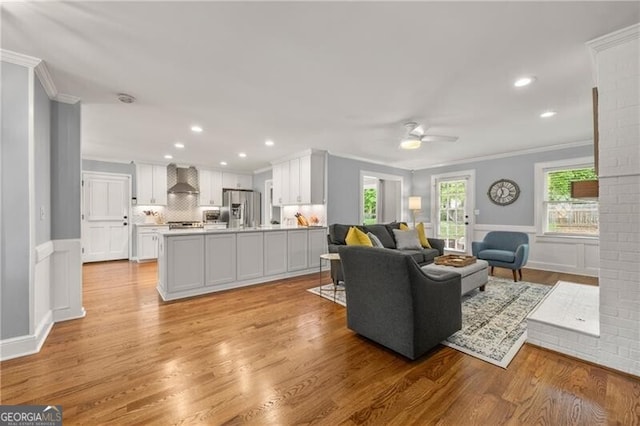 living area featuring recessed lighting, ceiling fan, ornamental molding, and light wood finished floors