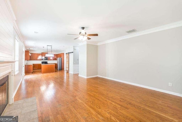 unfurnished living room with baseboards, visible vents, ornamental molding, and a tiled fireplace
