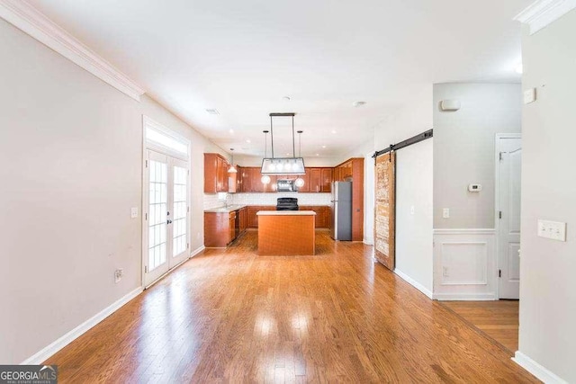 kitchen with freestanding refrigerator, brown cabinets, a kitchen island, and light wood-style flooring