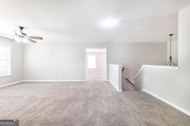carpeted spare room featuring a ceiling fan and baseboards