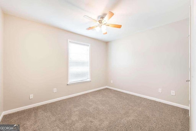 carpeted spare room featuring baseboards and a ceiling fan