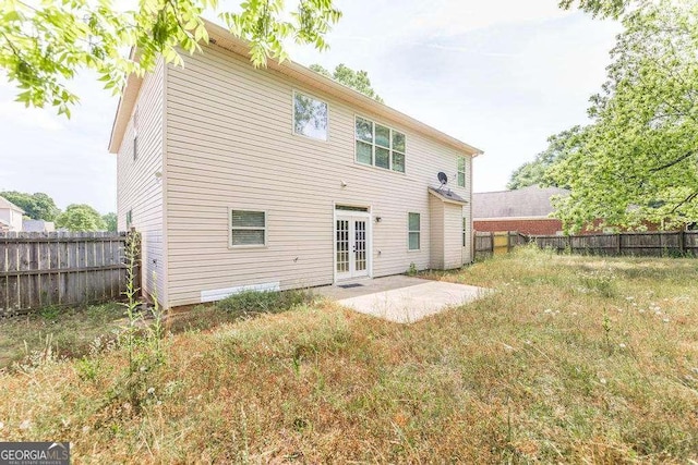 rear view of property featuring a fenced backyard, a patio area, and french doors