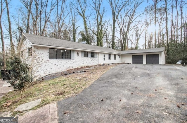 ranch-style home with an attached garage, aphalt driveway, and brick siding
