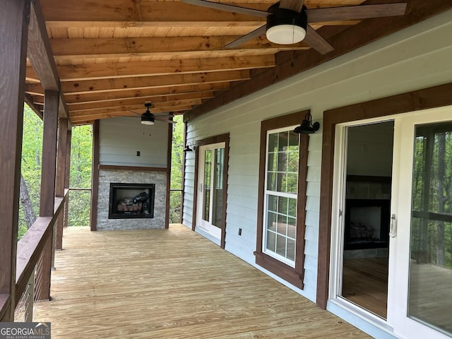 wooden deck with an outdoor fireplace and ceiling fan