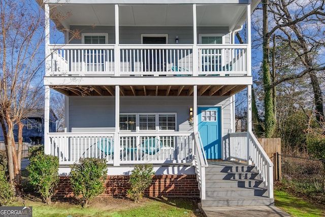 view of front of house featuring covered porch, fence, and a balcony