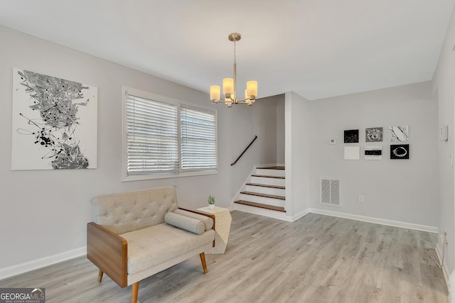 living area featuring visible vents, light wood finished floors, a chandelier, and stairway