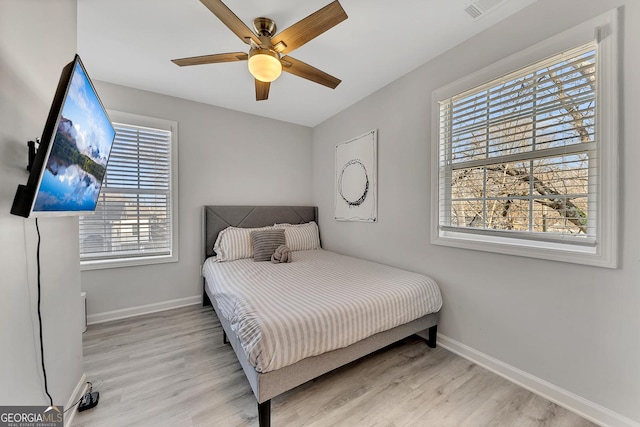 bedroom with baseboards, multiple windows, and light wood-style flooring