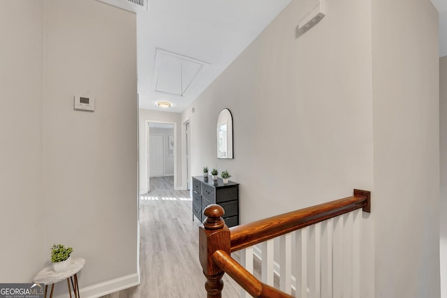 hallway with baseboards, an upstairs landing, light wood finished floors, and attic access