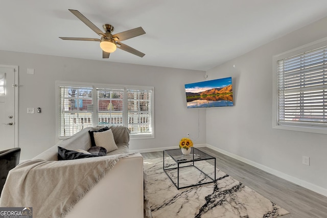 living area featuring a ceiling fan, baseboards, and wood finished floors