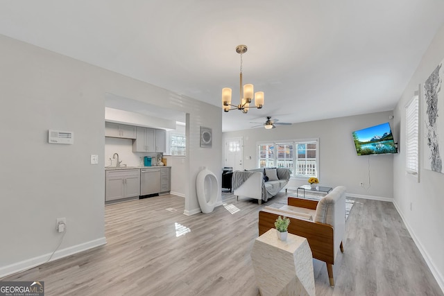 dining space featuring baseboards, plenty of natural light, ceiling fan with notable chandelier, and light wood-type flooring