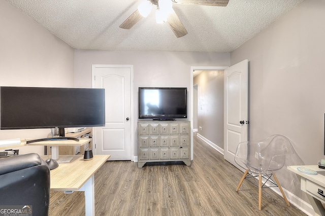 interior space with a textured ceiling, ceiling fan, baseboards, and wood finished floors