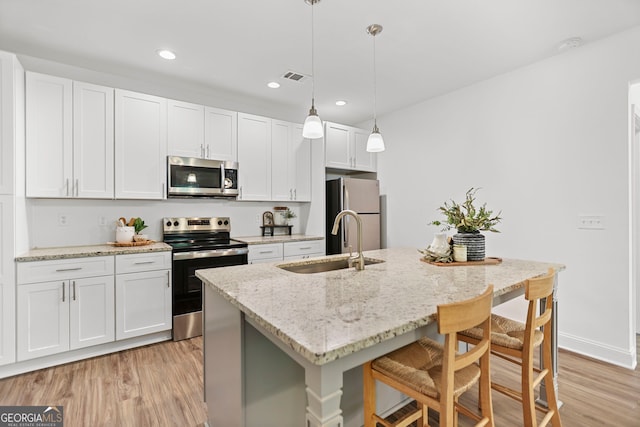 kitchen with a breakfast bar area, visible vents, a sink, light wood finished floors, and stainless steel appliances
