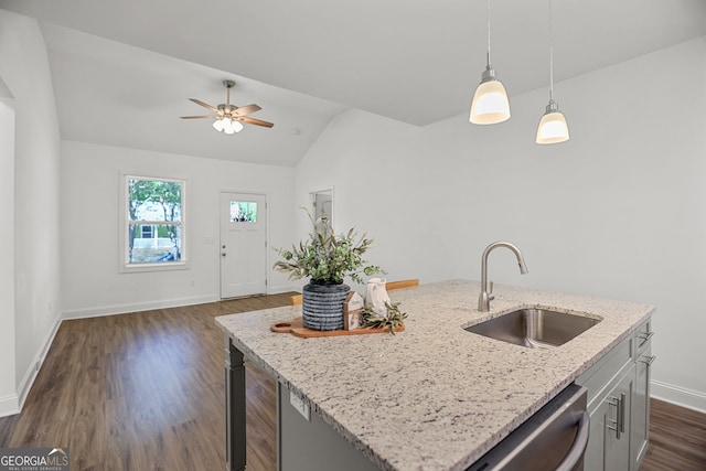 kitchen with light stone countertops, a sink, dark wood finished floors, baseboards, and vaulted ceiling