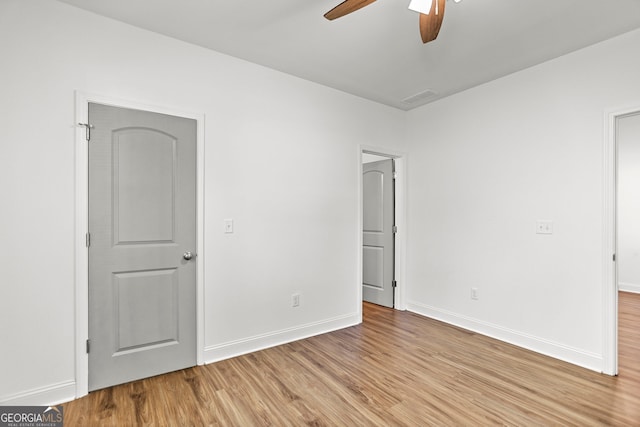unfurnished bedroom with baseboards, wood finished floors, and visible vents
