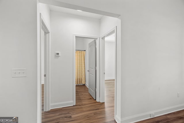 hall featuring baseboards and wood finished floors