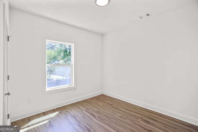 spare room featuring baseboards, wood finished floors, and visible vents