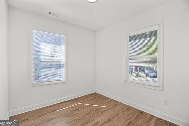 unfurnished room with baseboards, visible vents, and wood finished floors