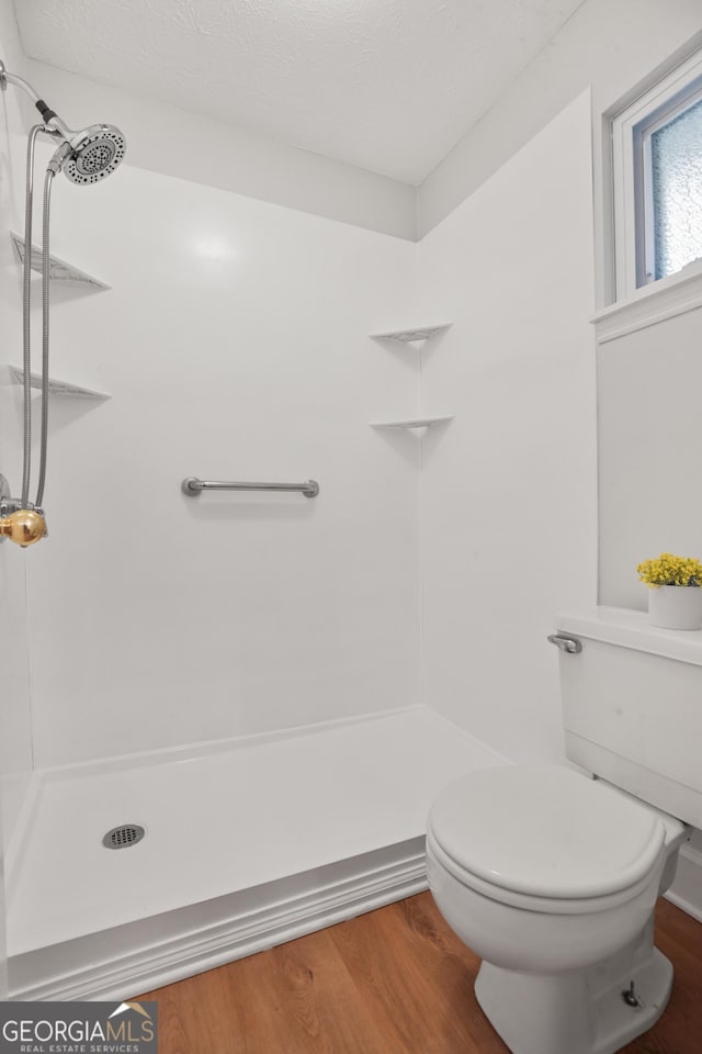 bathroom featuring wood finished floors, a shower, and toilet