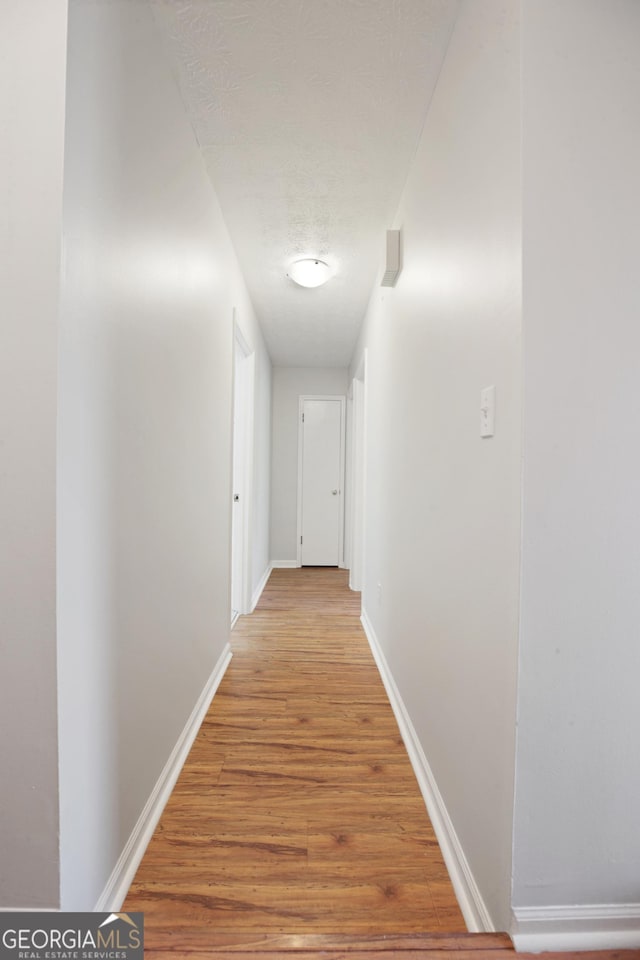 hall with light wood-style flooring and baseboards