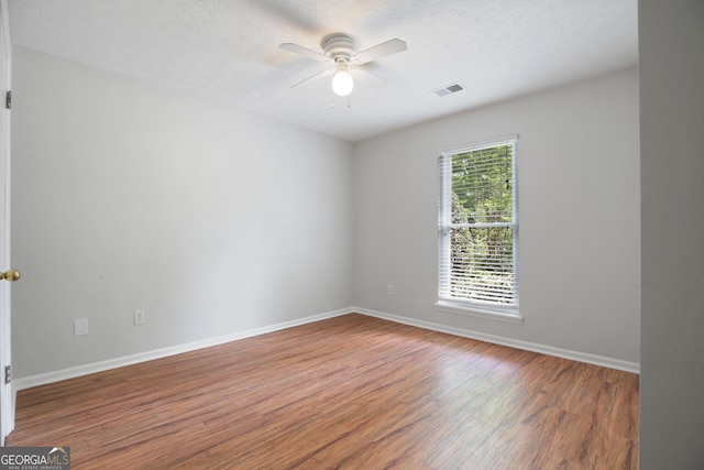 unfurnished room with ceiling fan, wood finished floors, baseboards, and a textured ceiling