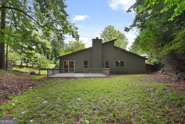 rear view of house featuring a chimney, a yard, and a wooden deck