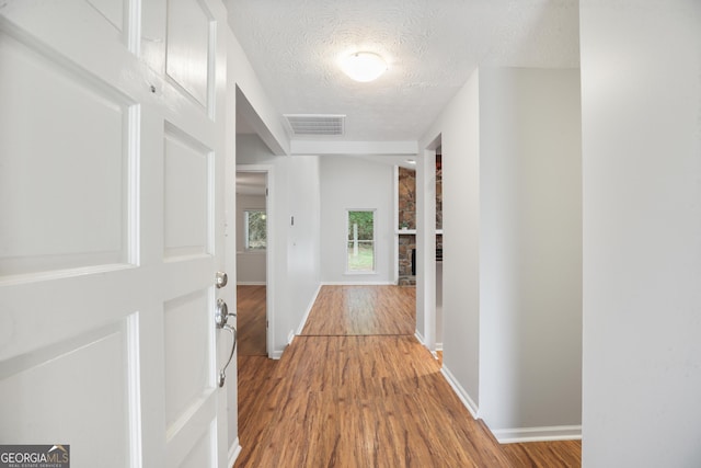 hall featuring wood finished floors, a textured ceiling, and baseboards