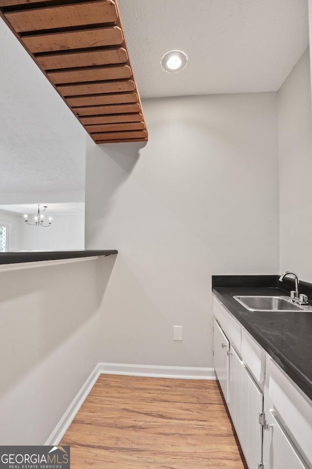 laundry room featuring a sink, light wood-type flooring, baseboards, and a chandelier