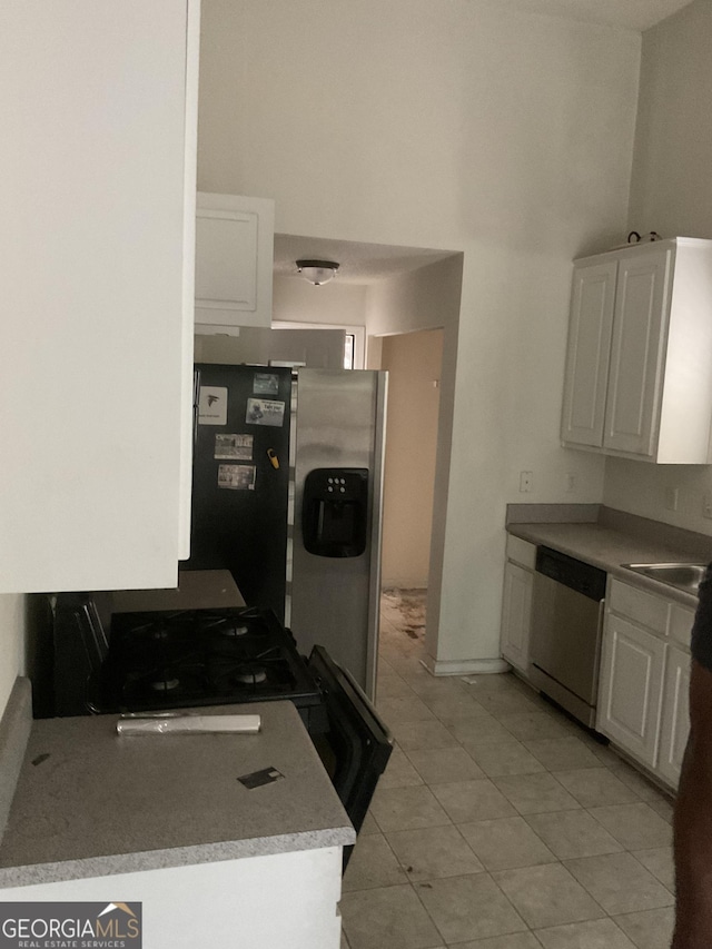 kitchen featuring white cabinets, light countertops, stainless steel appliances, light tile patterned floors, and a towering ceiling