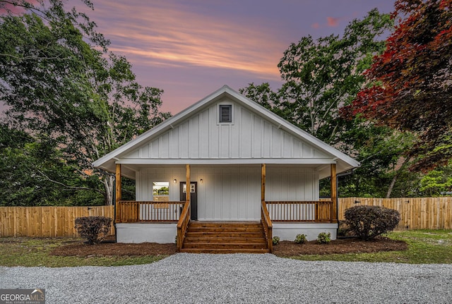 bungalow-style house with fence, board and batten siding, and a porch