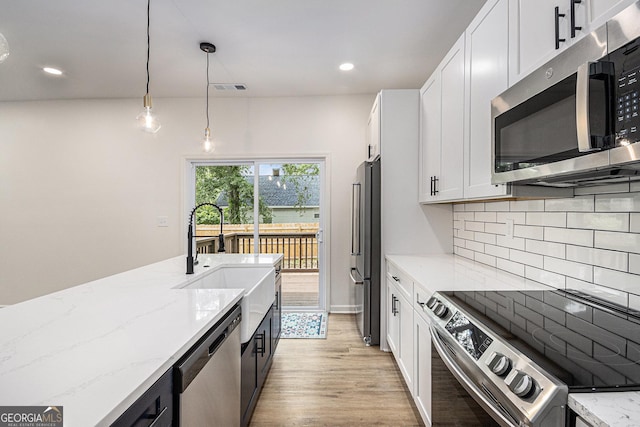 kitchen featuring appliances with stainless steel finishes, a sink, white cabinetry, tasteful backsplash, and visible vents