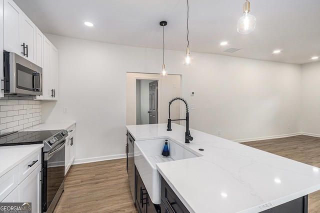 kitchen featuring appliances with stainless steel finishes, decorative backsplash, baseboards, and light wood-type flooring