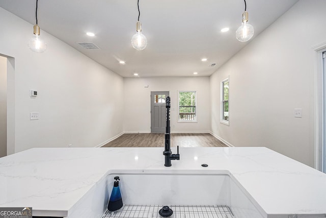 interior space featuring a sink, recessed lighting, wood finished floors, visible vents, and pendant lighting