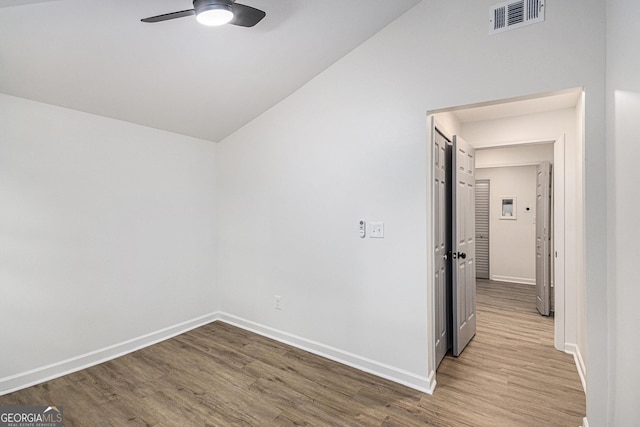 spare room featuring vaulted ceiling, a ceiling fan, wood finished floors, and visible vents