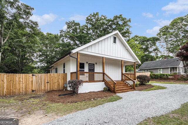 view of front facade with fence, covered porch, and board and batten siding