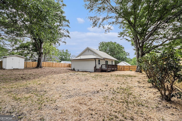 exterior space with a storage unit, a fenced backyard, a wooden deck, and an outbuilding