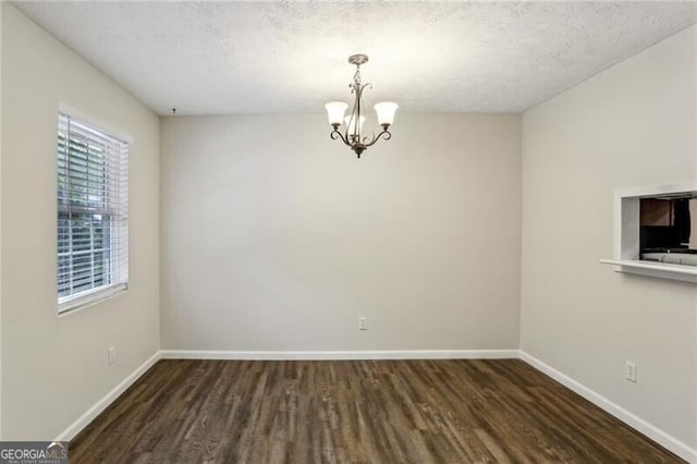 3135 Reeves St SE, Smyrna, GA 30080 - unfurnished dining area featuring a textured ceiling, baseboards, a chandelier, and wood finished floors
